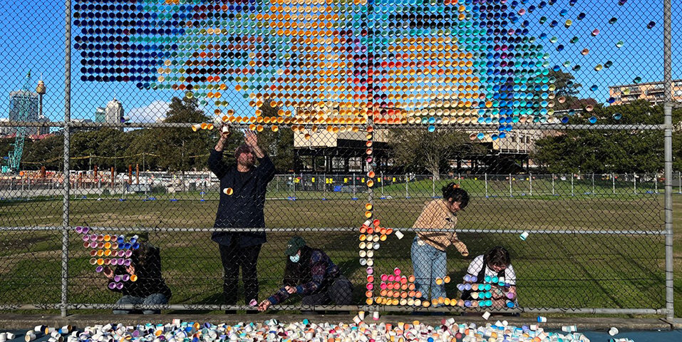 Art Department creating a mural of painted cups in a fence on set